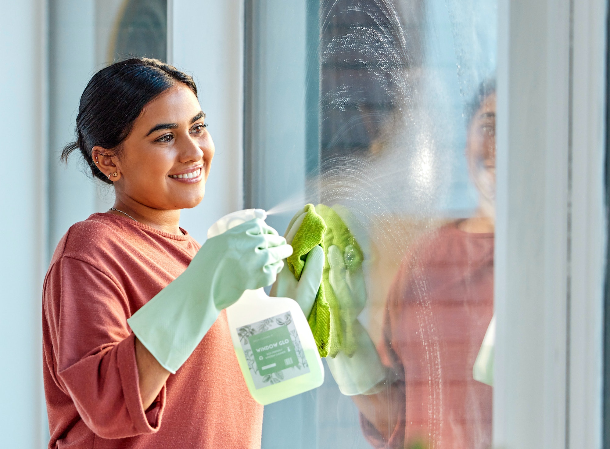 Glass, spray or woman cleaning a window with liquid soap or chemical product for dusty bacteria or