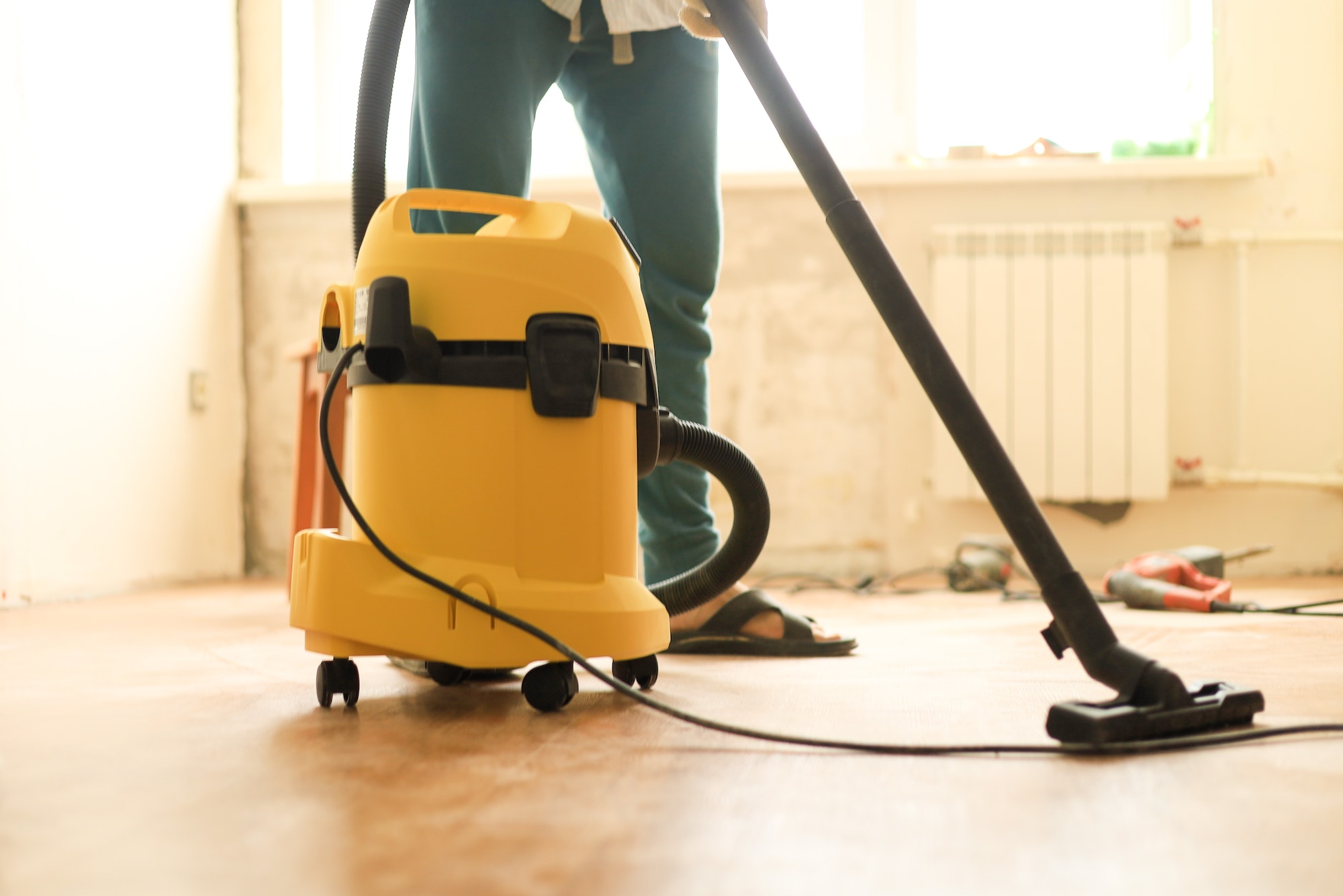 A man is cleaning the room during repairs using a construction vacuum cleaner